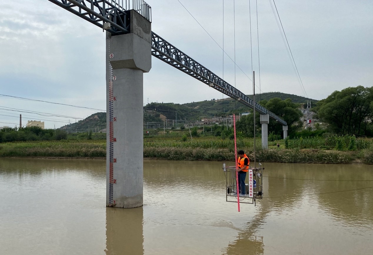 测报员白伟伟正在吊厢上进行水文测验.