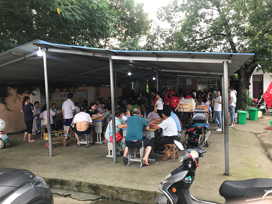 受灾群众聚集在桥头小学安置点大棚下,准备吃饭。