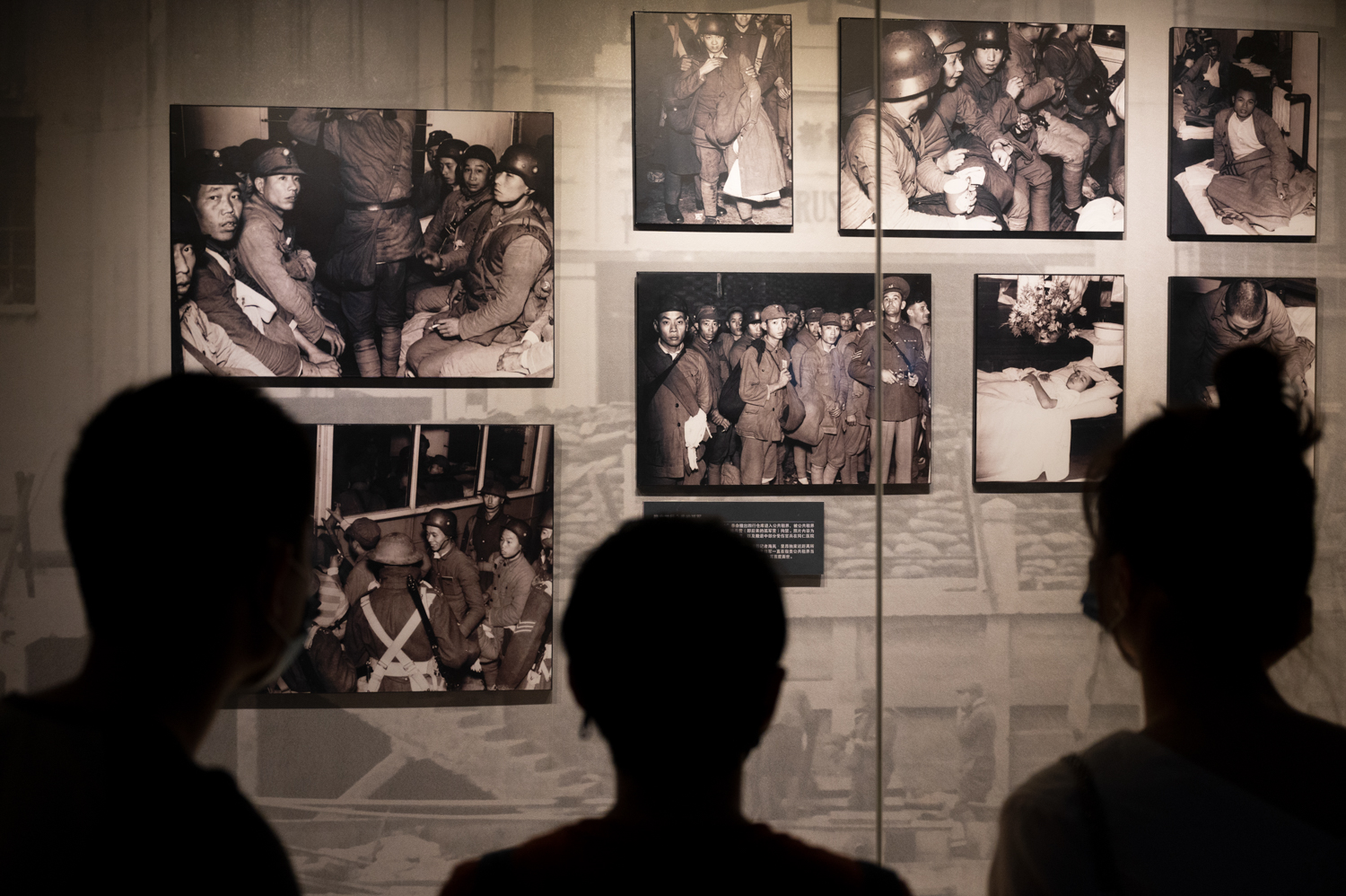 上海四行仓库，三位游客正在浏览相关的历史图片。