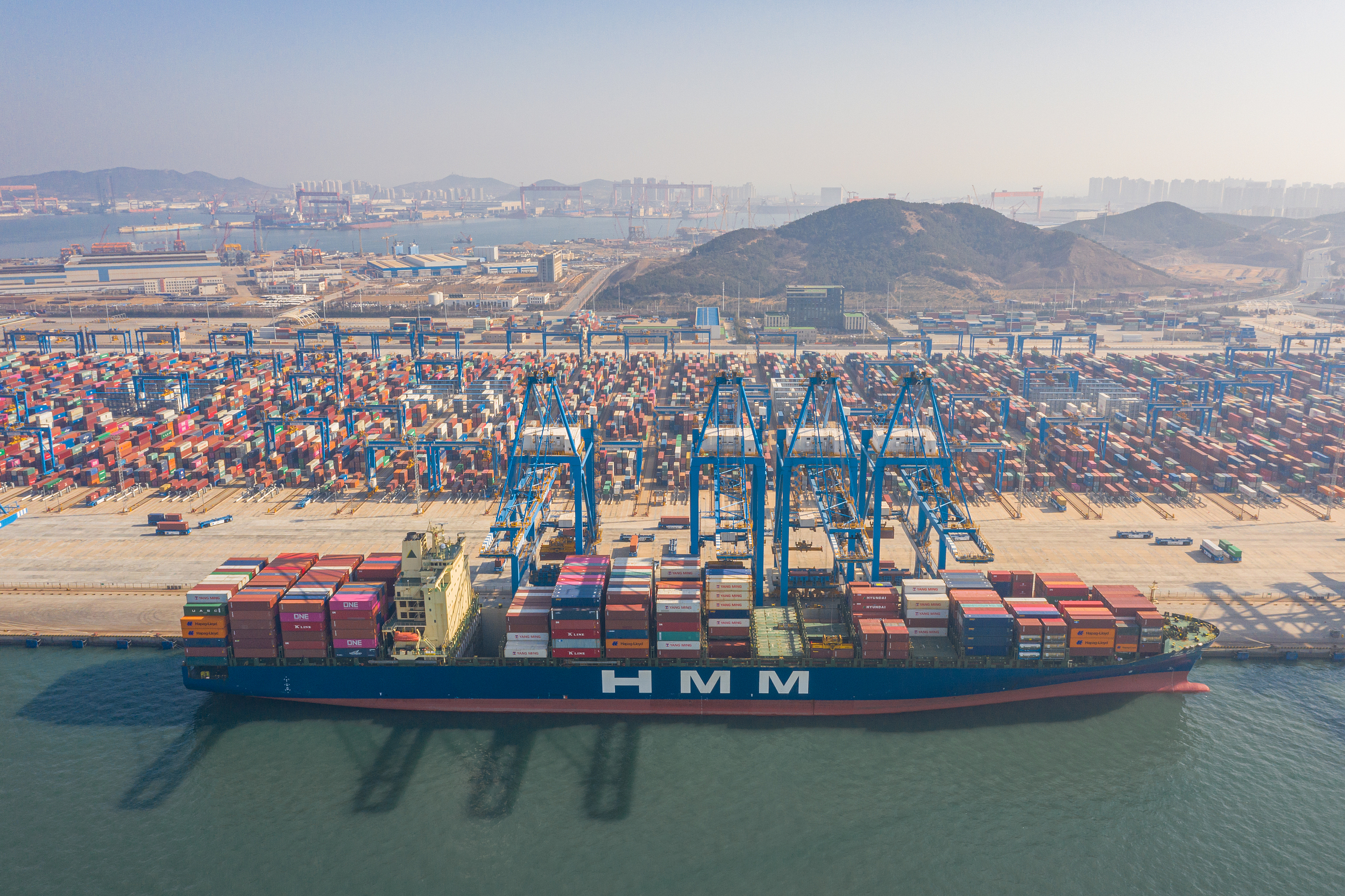 2021年2月21日，航拍青岛港繁忙的码头，集装箱排列成行，货轮装载满满 图源：视觉中国