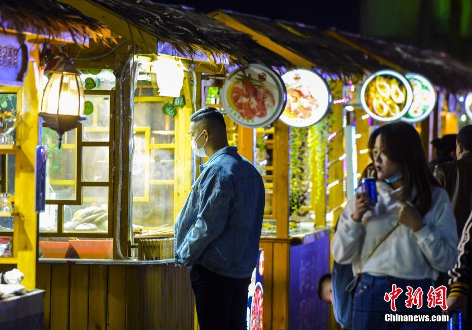 4月10日晚,市民在新疆维吾尔自治区乌鲁木齐市延安路欢乐时光夜市逛街、品美食。近日,乌鲁木齐的日夜星光、野马、欢乐时光等多个夜市陆续迎客。 中新社记者 刘新 摄