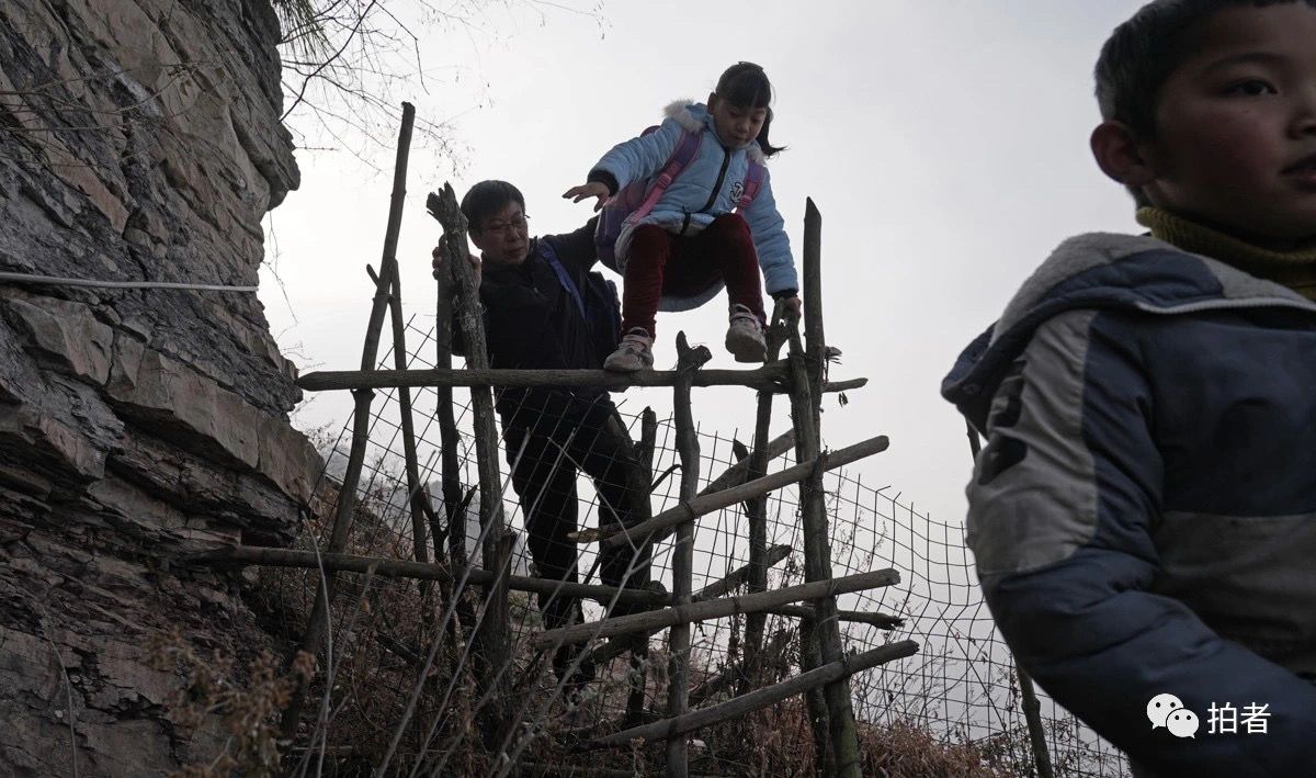 △ 2021年1月，李桂林接送6个从田坪村来上学的学生，他协助学生从悬崖路上一处设有防止牛羊的围栏翻过。新京报记者陈杰 / 摄影报道