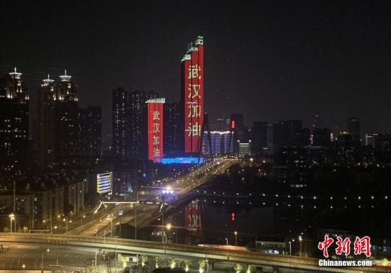 资料图：1月28日，武汉市汉江边上的两栋建筑亮起“武汉加油”字样霓虹灯。中新社记者 杨程晨 摄