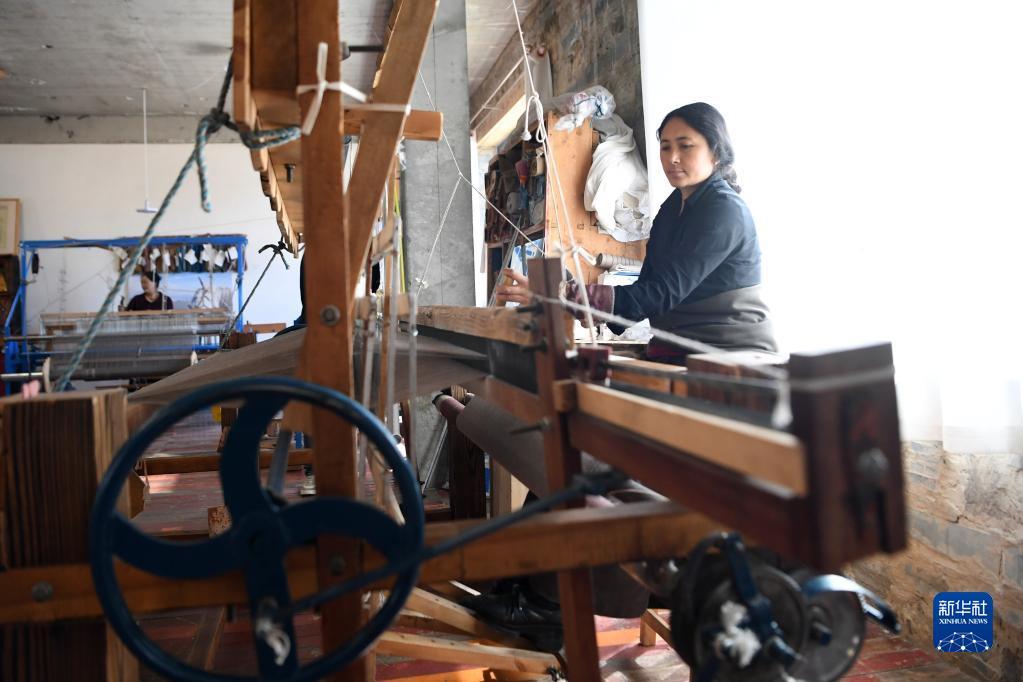 村民们在藏族手工艺品车间里制作藏毯,披肩,藏服,围巾等手工艺品,在