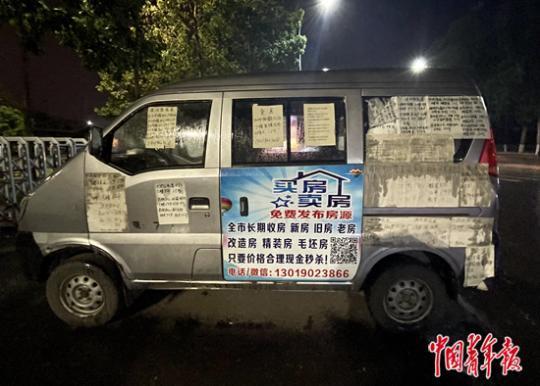 停在鹤岗人民广场正门入口处的面包车,车身贴满卖房的字条。