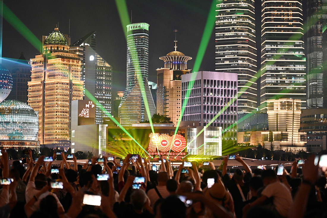 2021年6月30日晚,游客在外滩观看"永远跟党走"黄浦江主题光影秀.