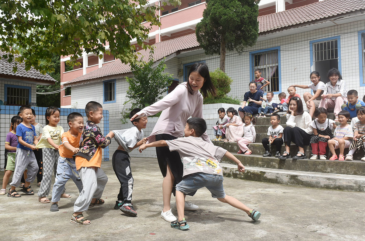 2021年9月7日,石盘寨小学,王锐茜老师正在和孩子们玩“老鹰捉小鸡”游戏。