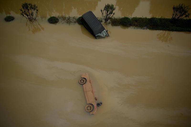 7月22日，河南郑州，暴雨过后，车辆躺在洪水中。