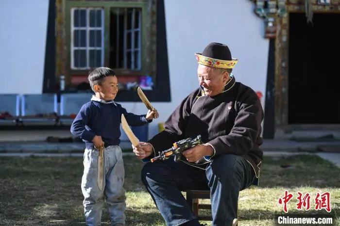 资料图：米林县扎西绕登乡彩门村64岁的洛桑带着孙子巴桑在院子的草地上玩耍。何蓬磊 摄