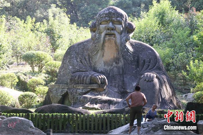 7月9日，一名小朋友在家长带领下，在泉州清源山的老君岩造像边玩耍。蒋启明 摄
