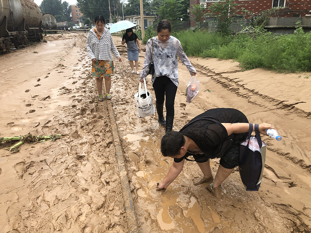 洪水过后，一条被淤泥覆盖的铝厂铁路专线成为东竹园村部分村民通往镇区的通道。一位村民从这里路过时，鞋子被淤泥陷住。  