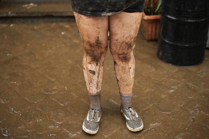 当地时间7月16日，比利时韦维耶，一名女子站在屋外清理淤积在家中的泥和水。