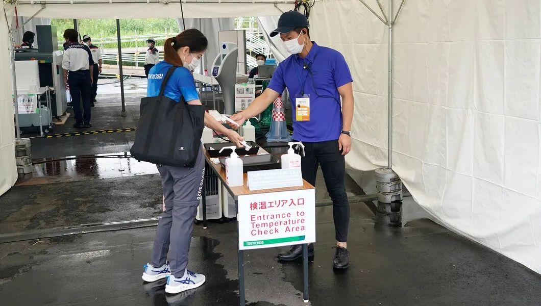 为了降低新冠疫情传播风险，进入奥运场馆前，志原者要进行体温测量。图/Tokyo 2020