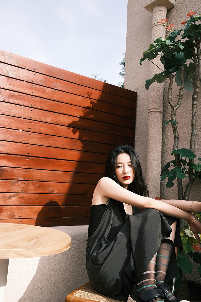 照片中,孙佳雨身着黑色背带长裙在微风中随意摆弄长发,慵懒随性中透着