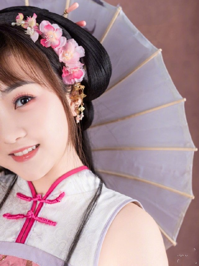 下图里,林妙可身穿桃红色无袖裙装,撑着油纸伞低头浅笑,完全就是"