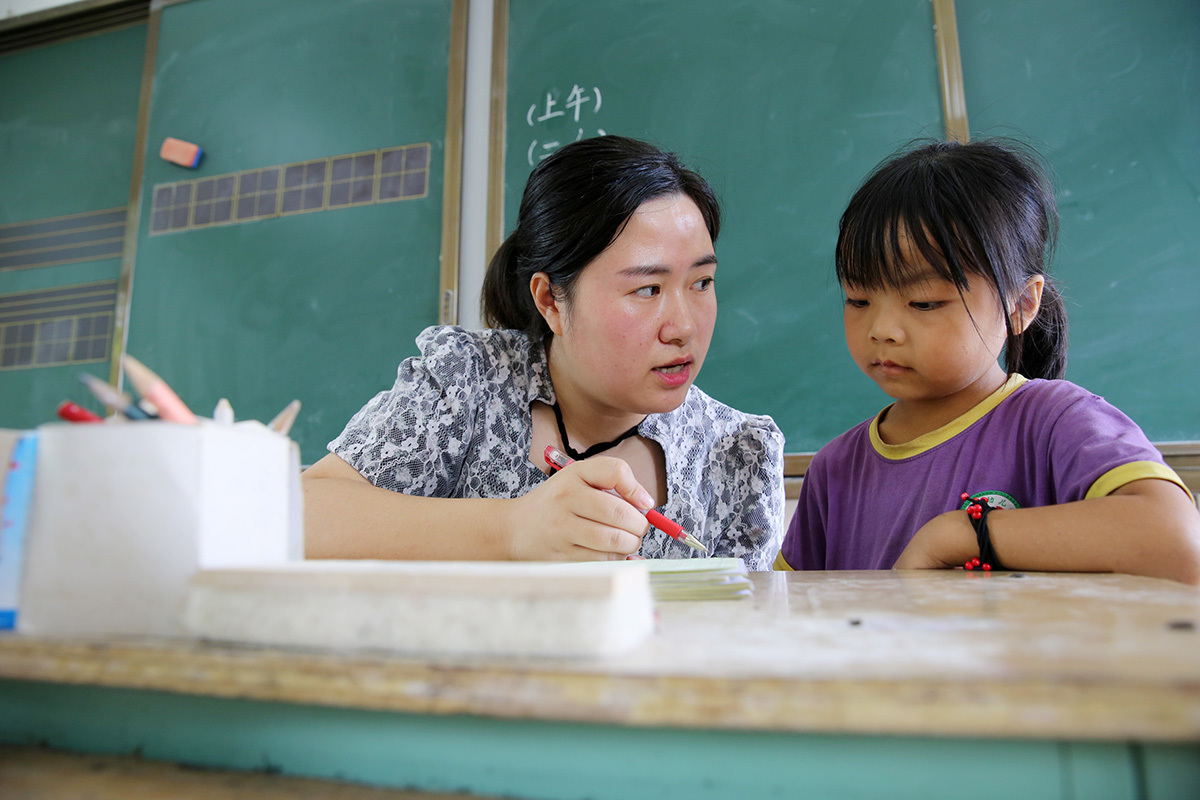 2021年9月7日,石盘寨小学,1996年出生的徐华玉老师正在为学生批改作业。