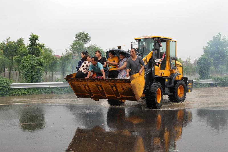 7月21日，在位于新107国道附近的河南省许昌市长葛市大周镇小河董村，救灾人员利用铲车疏散和转移被困村民。