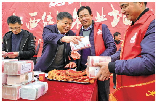 2019年1月18日，安义县“粮王”凌继河(右三)给农民员工发放奖金。