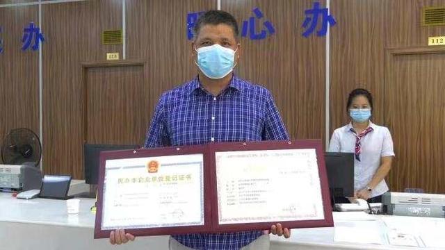 9月14日,金华市婺城区英华时代教育培训有限公司负责人倪俞华从工作人员手中接过两本全新的证件。 钱江晚报 图