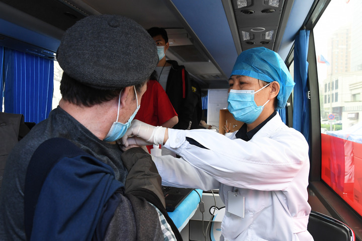 （ 4月11日，在北京市海淀区羊坊店街道小马厂社区新冠疫苗临时接种点，医护人员在移动疫苗接种车上为接种人员接种新冠疫苗。新华社记者 任超 摄）