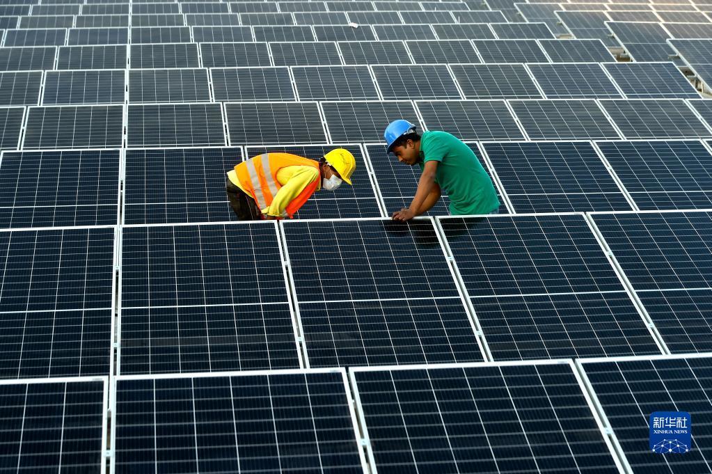 2021年1月3日，在位于孟加拉国首都达卡郊区的利德成集团厂区，工人们在房顶组装光伏模组。从2020年开始，中资制衣类企业——利德成集团在其位于孟加拉国达卡的厂区内建设光伏电站，以降低对传统能源的依赖，减少碳排放，从绿色发展的角度助力“一带一路”建设。新华社发