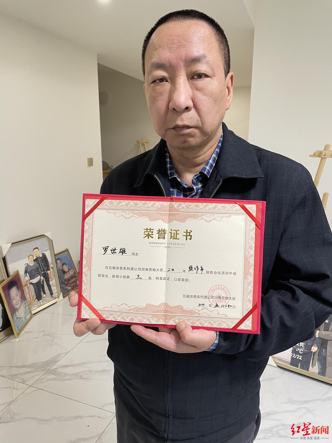 神情哀伤的罗军手捧儿子的荣誉证书