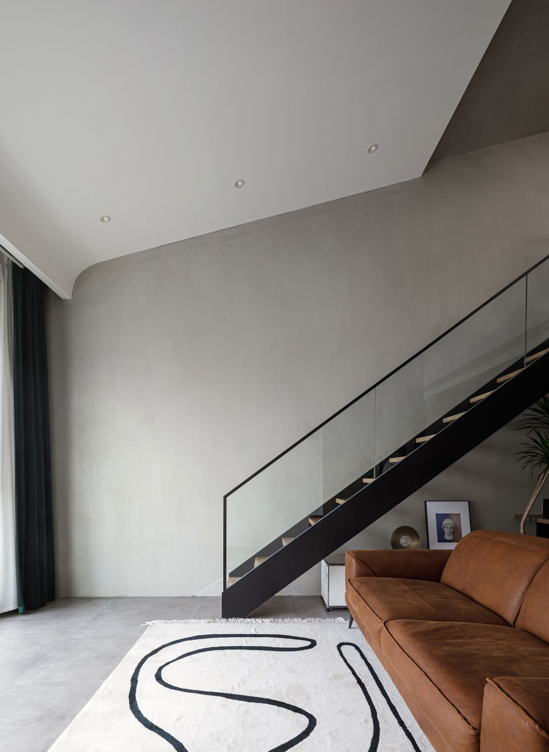 通过白色随坡吊顶与水泥顶面的材质区分,限定出客厅空间.