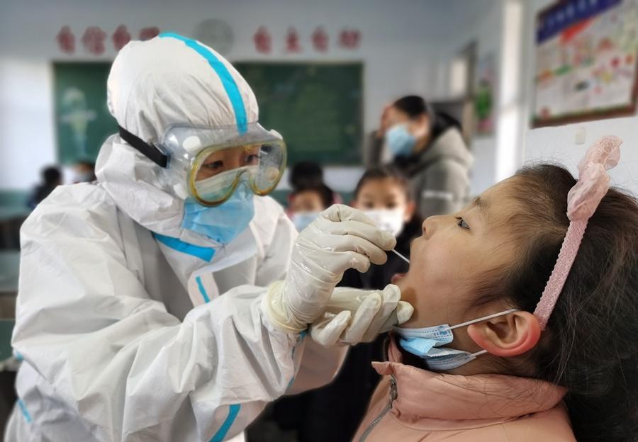1月6日,在河北省邢台市南园路小学,医务人员为学生进行核酸检测采样。图/网络