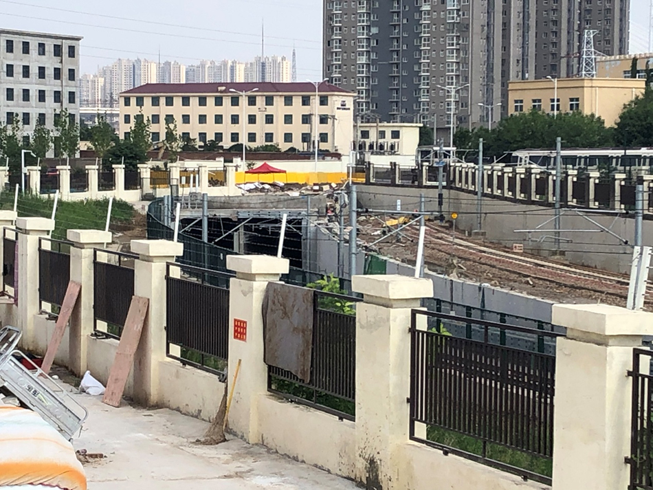 隧道口远景,两条线轨从中延伸出来,沿槽状坡道爬升。