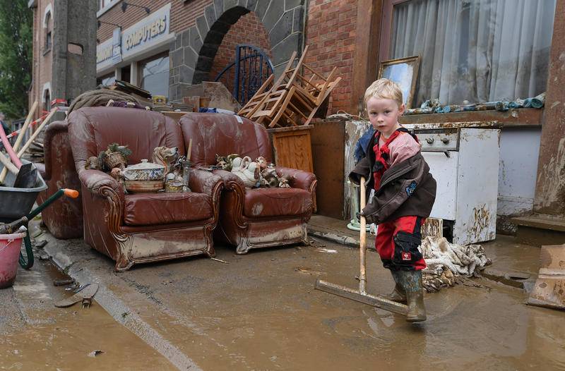当地时间7月17日，比利时罗什福尔镇，暴雨和洪水过后，小男孩帮忙清淤。