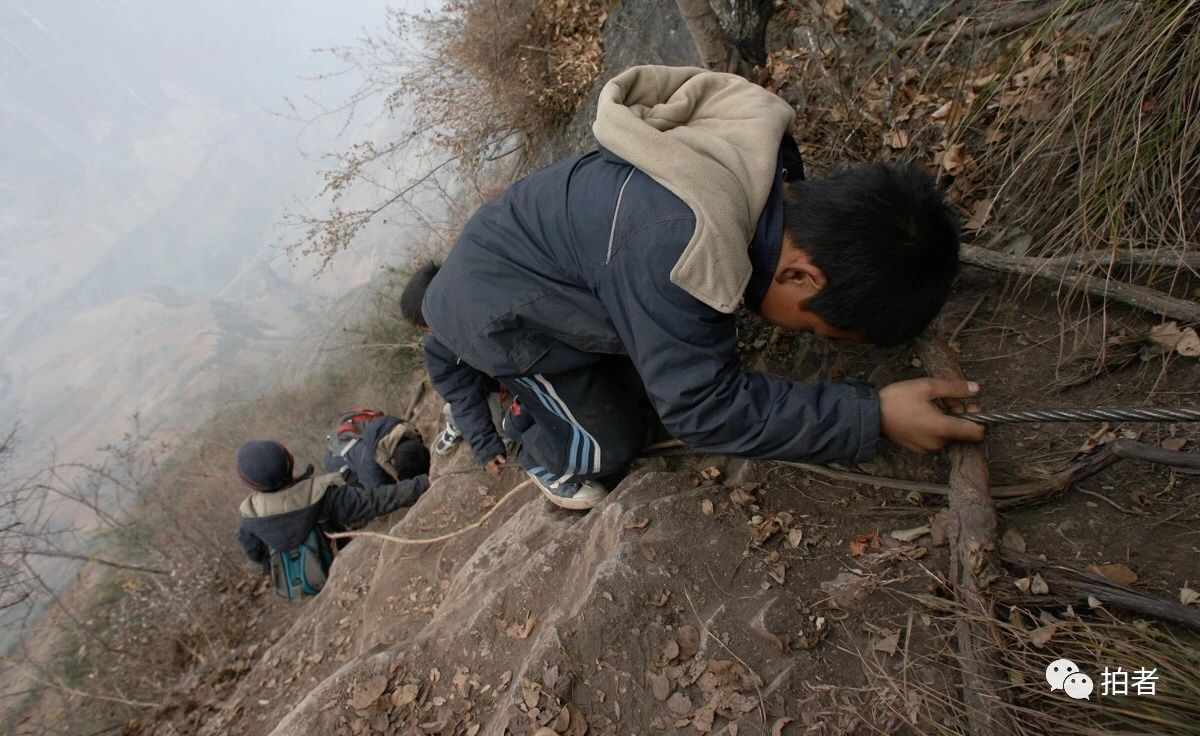 △ 2007年12月，在一些几乎垂直的悬崖上，学生们通过拉着钢索和藤条攀爬，李桂林夫妇一个在前一个在后，小心看护着。
