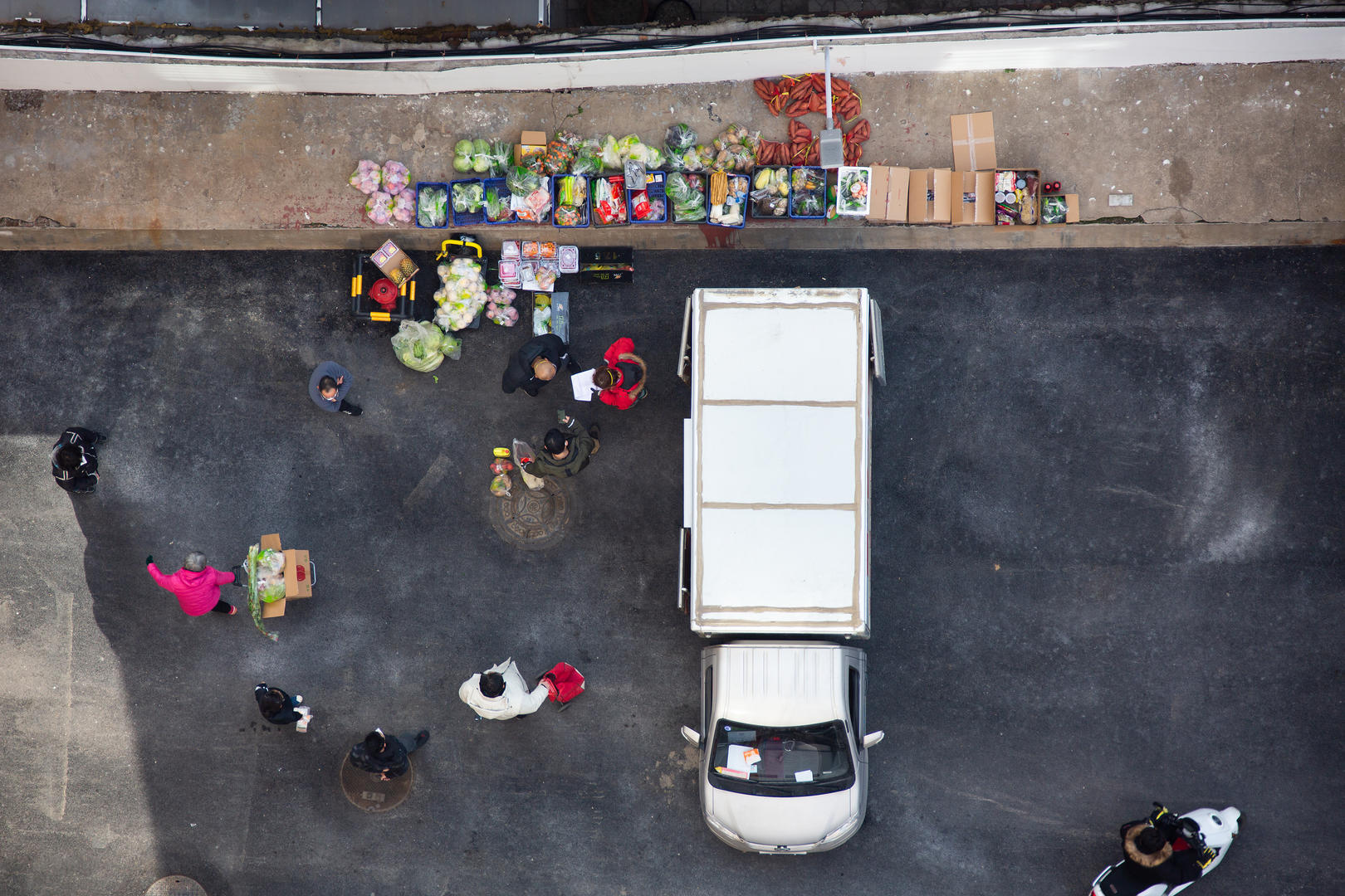 2020年2月19日，济南某小区内，居民们在十荟团微信群购买的蔬菜肉食水果到货，客户陆续下楼来领取。图据视觉中国