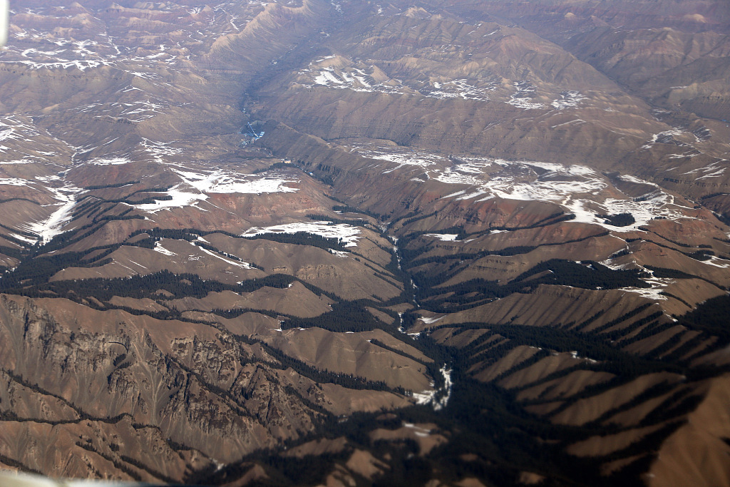 2021年3月10日,乌鲁木齐飞往阿克苏的飞机上,俯瞰新疆天山山脉,白雪覆盖气势雄壮。(图片来源:视觉中国)
