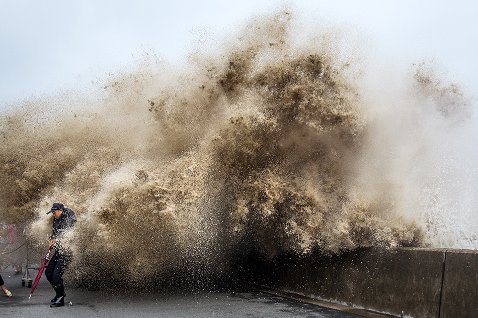 2013年9月21日,杭州,钱塘江下沙七格段,汹涌的潮水冲上堤坝,一名安保人员转身躲避。
