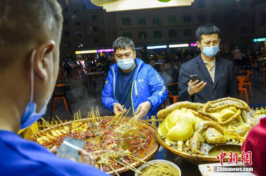 4月10日晚,市民在新疆维吾尔自治区乌鲁木齐市延安路欢乐时光夜市逛街、品美食。近日,乌鲁木齐的日夜星光、野马、欢乐时光等多个夜市陆续迎客。 中新社记者 刘新 摄