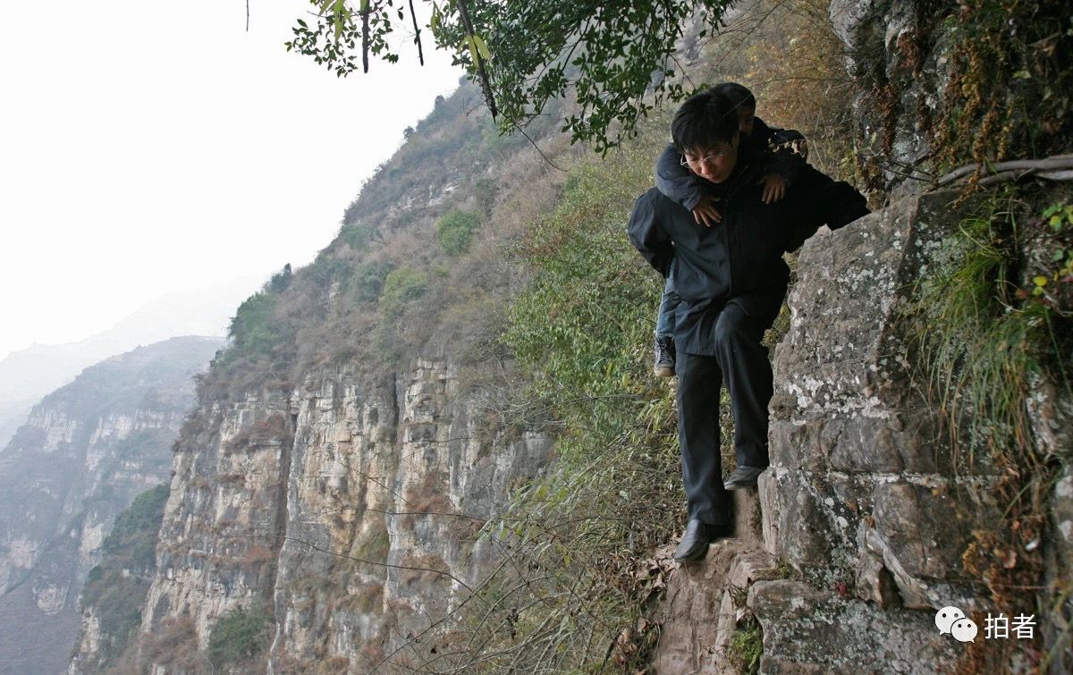 △ 2007年12月，李桂林背着一年级的学生，手抓钢索，在悬崖峭壁上行走。