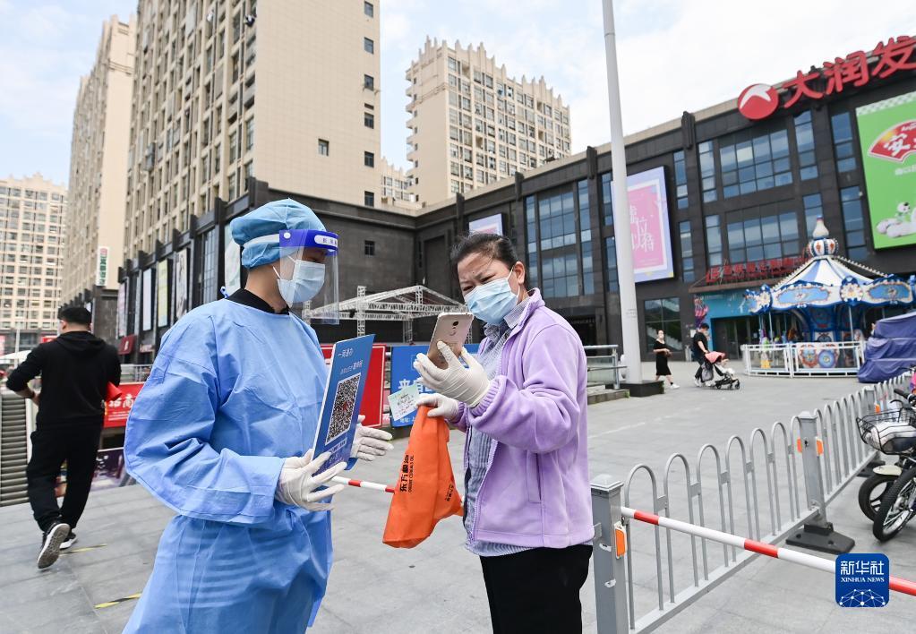 在上海市嘉定区一家超市,工作人员在商超入口处核验购物者的防疫码(5月9日摄)。