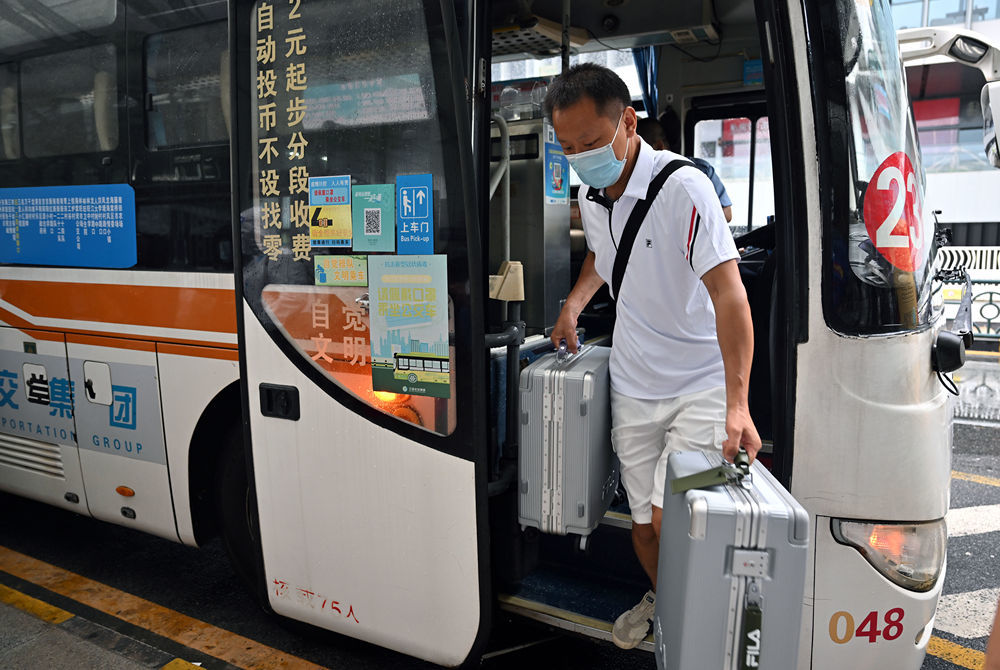 ↑8月9日，滞留三亚的游客走下大巴，准备进入三亚凤凰国际机场。