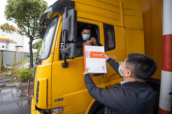4月13日，杭州传化公路港的工作人员在货车驶离公路港时为司机送上装满食品的礼包。新华社记者江汉摄