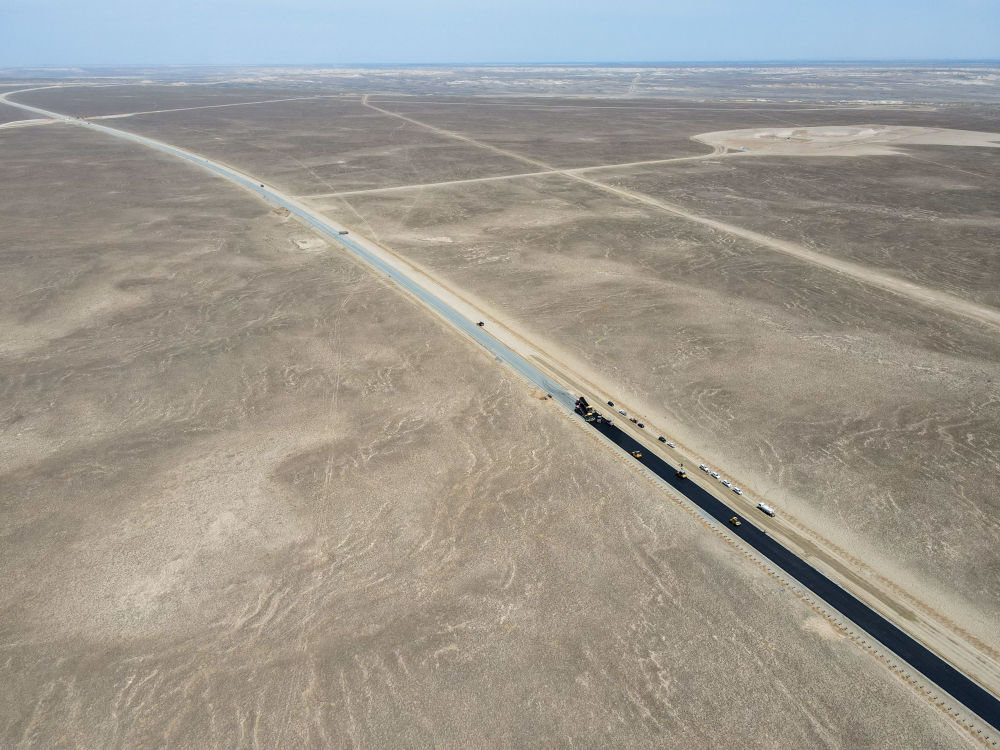 这是穿越古尔班通古特沙漠的阿勒泰至乌鲁木齐高速公路施工画面。（无人机照片 新华社记者高晗 摄）