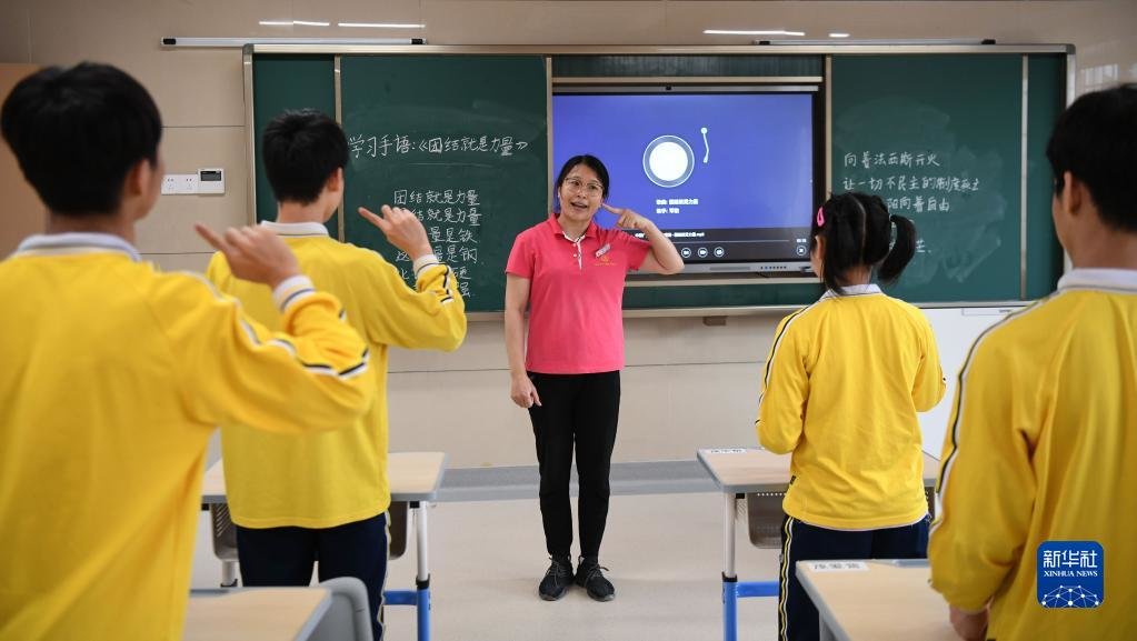 广东茂名市社会福利中心工作人员曾传莹（中）在给孩子上手语课（2021年4月27日摄）。新华社记者 邓华 摄