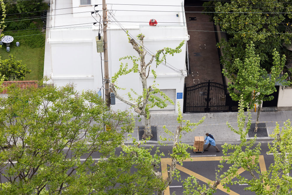 ↑4月16日,在上海市徐汇区高安路上,一位封控在家的老人从阳台往下探望。