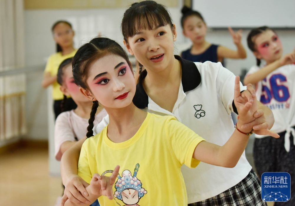 6月10日,在浙江省武义县新宅小学,戏曲老师向小朋友传授婺剧表演基本