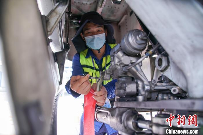 图为放行工程师在飞机前起落架插上转弯销。 陈冠言 摄