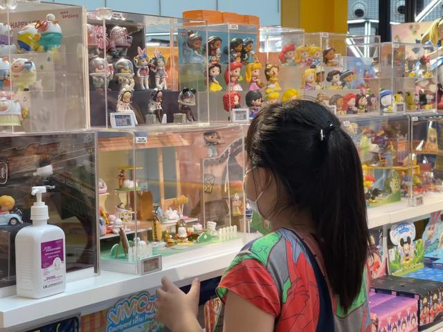 一名梳着马尾辫的小女孩正在注视着COOLABO宇宙朋友系列玩偶。 图/新京报贝壳财经记者于梦儿摄