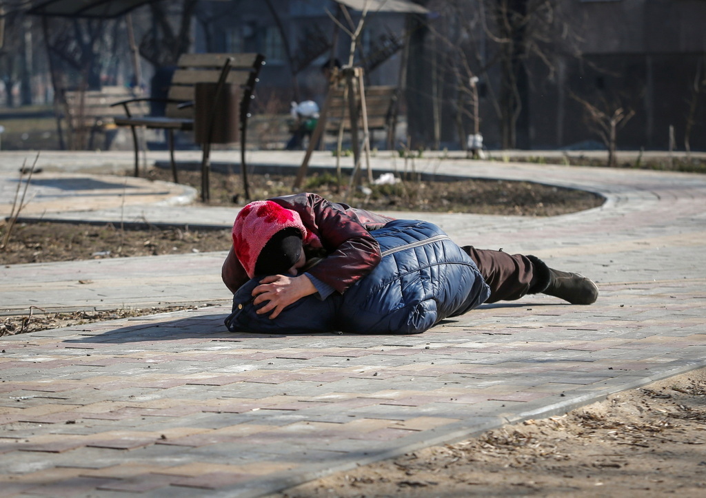 烏克蘭馬裡烏波爾,聽到炮擊聲後,一名婦女和她的兒子趴在地上躲避