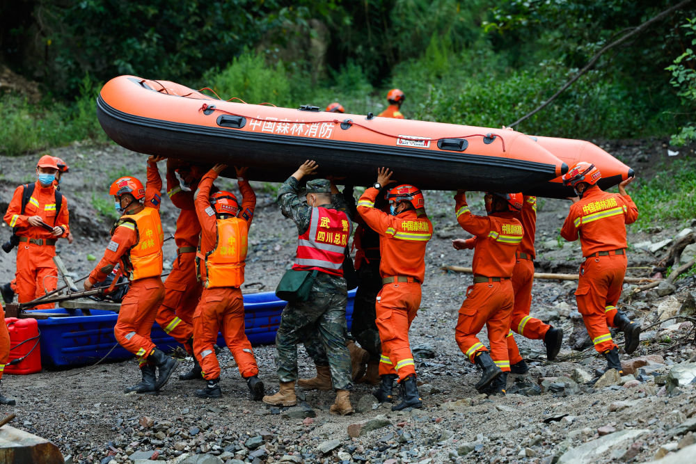 9月6日，救援队伍正在合力将橡皮艇运往河边，从水路绕过损毁道路。新华社记者 沈伯韩 摄