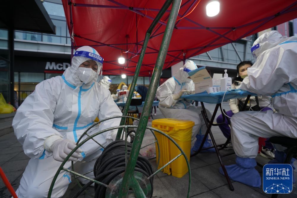 2021年9月26日,在哈尔滨市道里区,梅宏刚(左一)帮助一社区核酸采样点架设临时照明电源。新华社发(受访者供图)