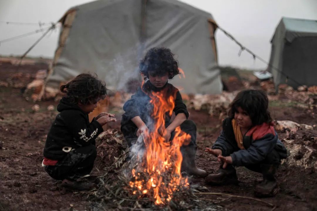 ▲ 在叙利亚西北部的伊德利卜难民营中，无家可归的儿童点燃捡来的废品取暖。