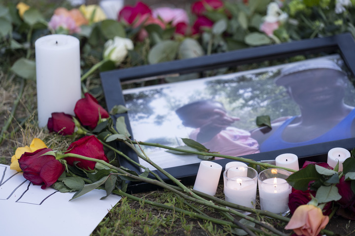 2021年5月25日，在美国华盛顿白宫附近举行的悼念弗洛伊德的集会上，人们将鲜花和蜡烛摆放在弗洛伊德和家人的照片旁。（新华社记者 刘杰 摄）